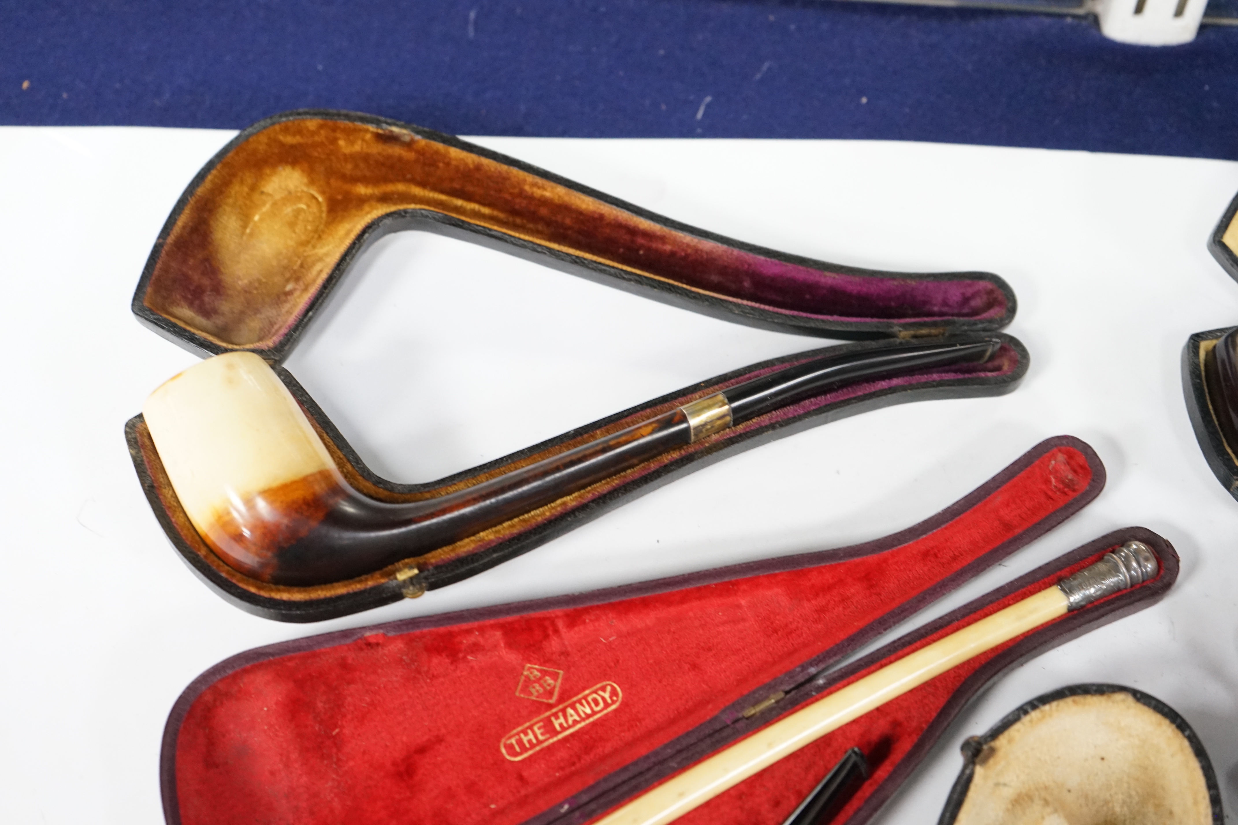 Seven cased pipes in varying sizes, some with amber mouthpieces, largest 19cm long